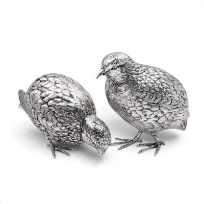 Two silver quails, one pecking and one standing, with finely chased feathers