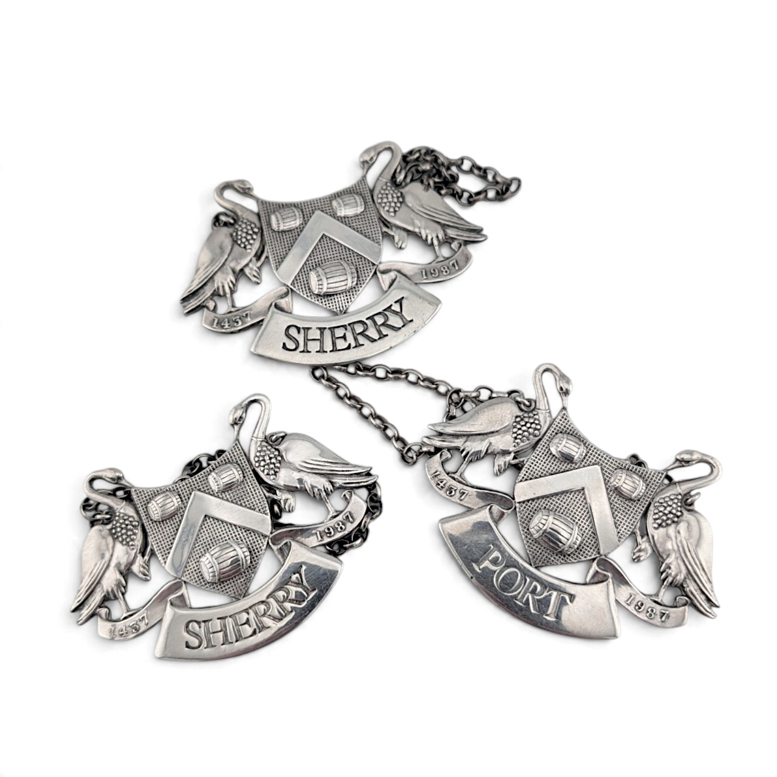 Three armorial wine labels laid flat with their chains